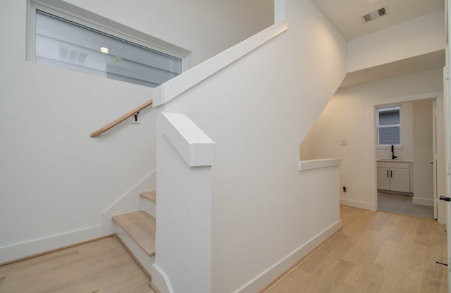 stairs with hardwood / wood-style flooring and sink