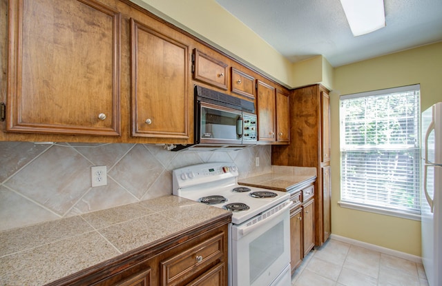 kitchen featuring white appliances, light tile patterned floors, and tasteful backsplash