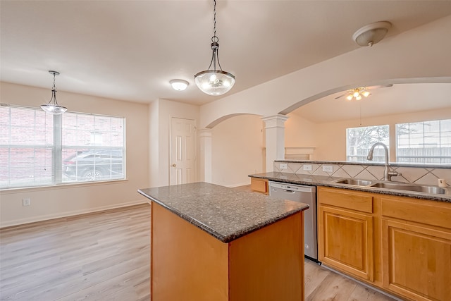 kitchen featuring a center island, light hardwood / wood-style floors, sink, decorative columns, and stainless steel dishwasher