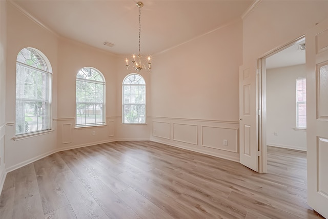 unfurnished room with crown molding, light hardwood / wood-style flooring, and a chandelier