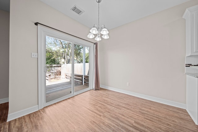 unfurnished dining area with wood-type flooring and an inviting chandelier