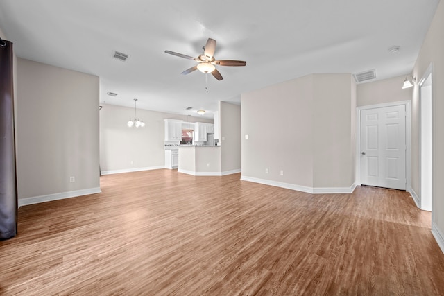 unfurnished living room with ceiling fan with notable chandelier and light wood-type flooring