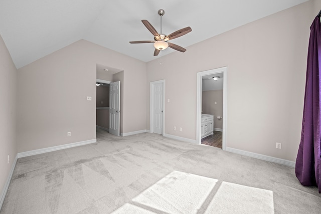 unfurnished bedroom featuring ensuite bath, ceiling fan, light colored carpet, and lofted ceiling