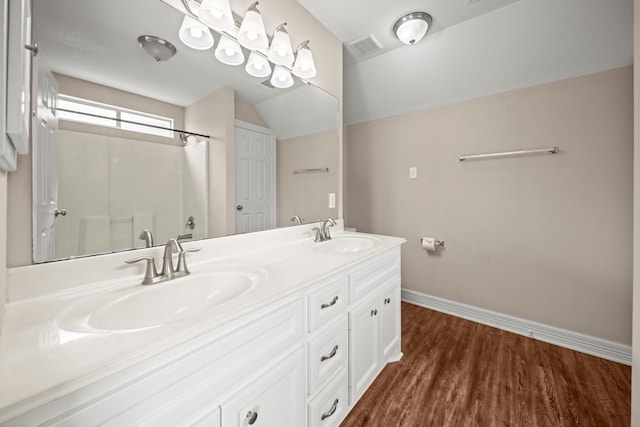 bathroom featuring wood-type flooring, vanity, vaulted ceiling, and walk in shower