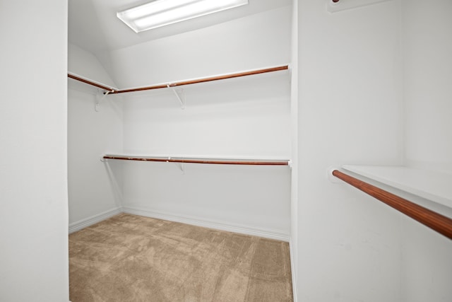 spacious closet featuring light colored carpet and lofted ceiling