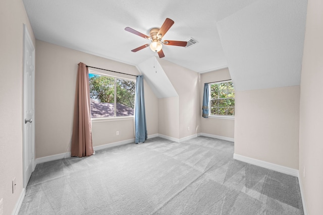 additional living space featuring a wealth of natural light, light colored carpet, and vaulted ceiling