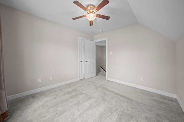 carpeted spare room with ceiling fan and vaulted ceiling