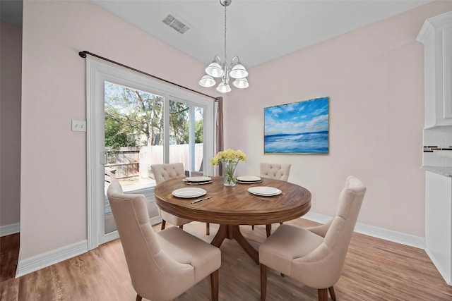 dining room with light hardwood / wood-style flooring and an inviting chandelier