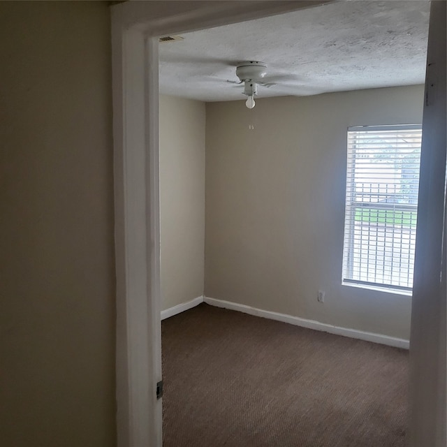 carpeted empty room featuring ceiling fan and a textured ceiling