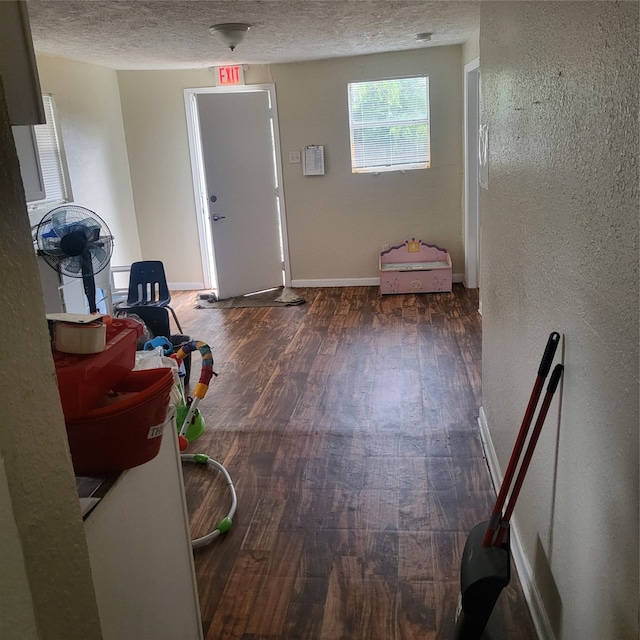 corridor with dark hardwood / wood-style flooring and a textured ceiling