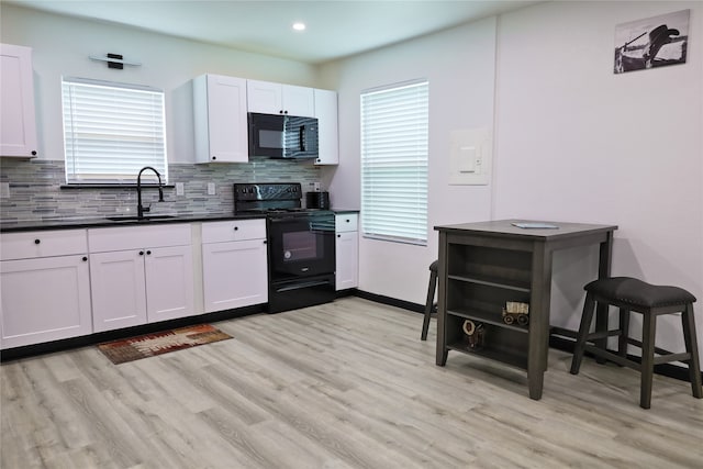 kitchen with black appliances, sink, white cabinets, and a healthy amount of sunlight