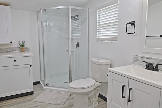 bathroom with a shower with shower door, hardwood / wood-style floors, toilet, and vanity