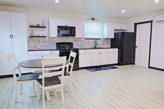 kitchen featuring light wood-type flooring, black appliances, tasteful backsplash, and sink