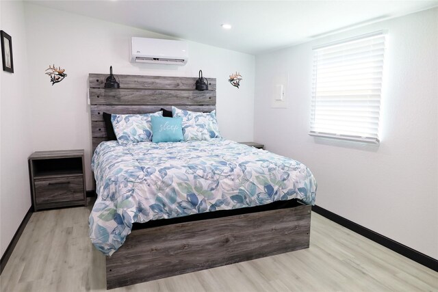 bedroom featuring light wood-type flooring and a wall unit AC