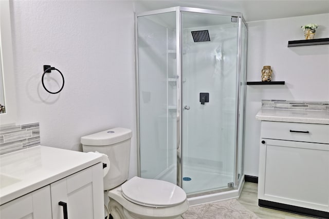 bathroom with a shower with door, vanity, toilet, decorative backsplash, and hardwood / wood-style flooring