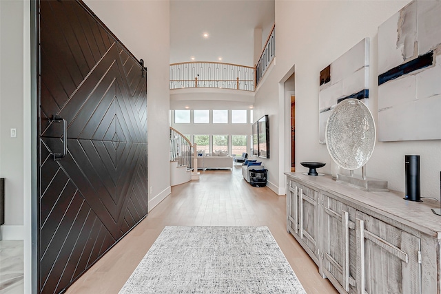 entrance foyer featuring a barn door, light hardwood / wood-style floors, and a high ceiling