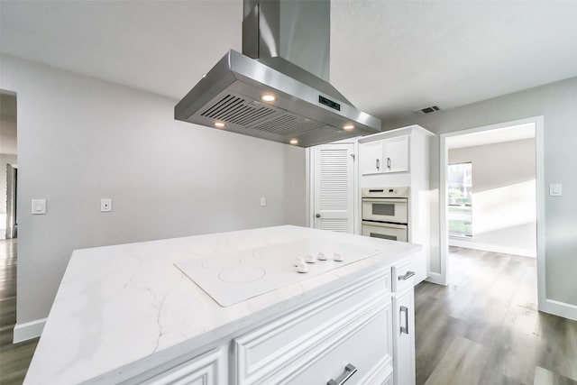 kitchen with white cabinetry, white appliances, dark hardwood / wood-style flooring, light stone countertops, and island exhaust hood