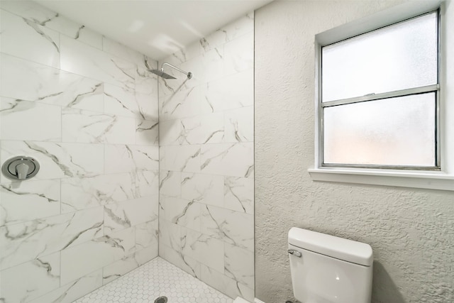 bathroom featuring tiled shower and toilet