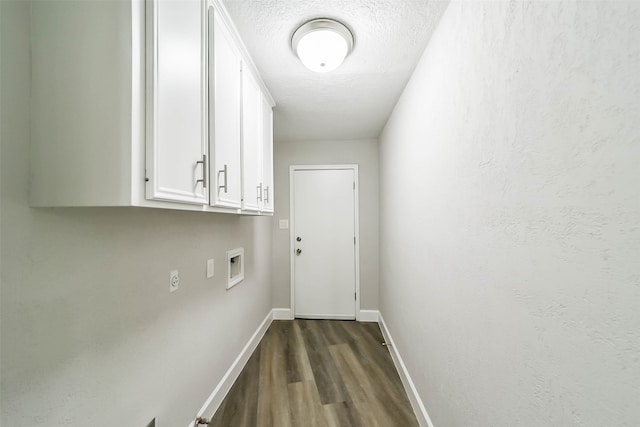 clothes washing area with washer hookup, dark wood-type flooring, a textured ceiling, and cabinets