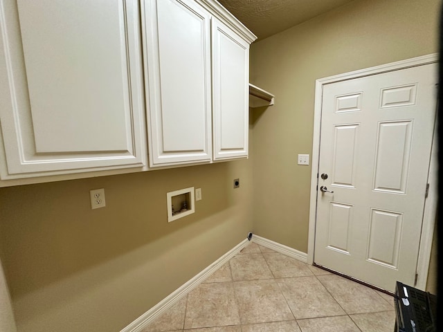 laundry room with a textured ceiling, hookup for a washing machine, cabinets, light tile patterned floors, and electric dryer hookup