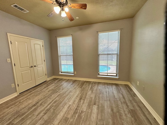 unfurnished bedroom with a textured ceiling, a closet, ceiling fan, and hardwood / wood-style floors