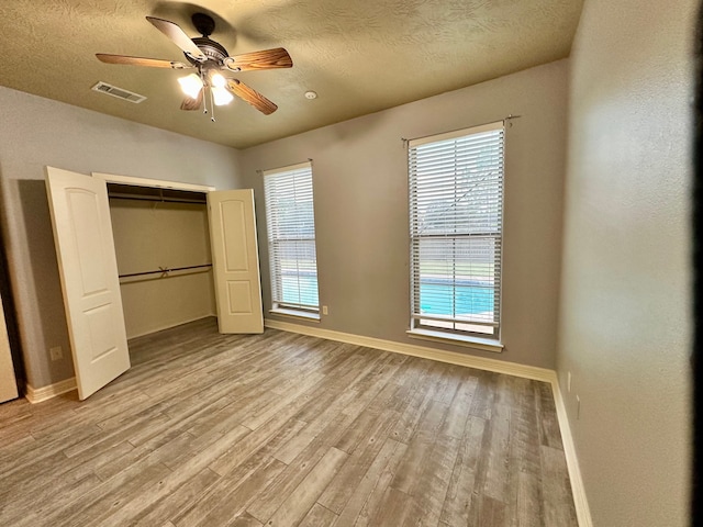 unfurnished bedroom with a closet, ceiling fan, a textured ceiling, and light hardwood / wood-style flooring