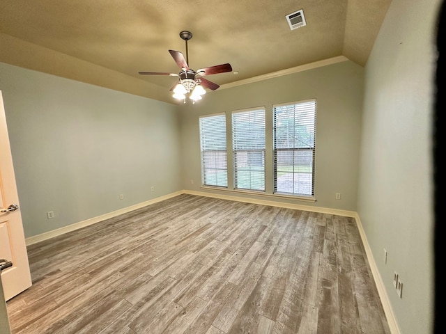 unfurnished room with light wood-type flooring, ornamental molding, a textured ceiling, ceiling fan, and vaulted ceiling