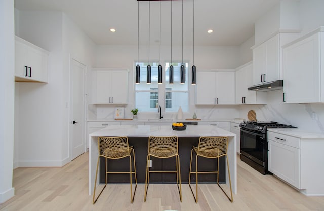 kitchen featuring light hardwood / wood-style flooring, decorative light fixtures, black range with gas cooktop, a center island, and white cabinets