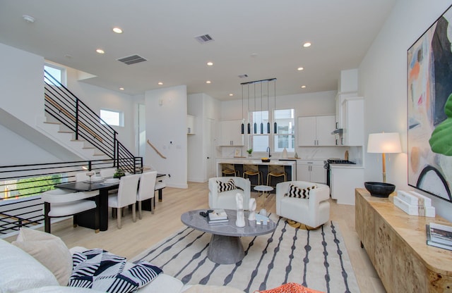 living room with light wood-type flooring, a wealth of natural light, and sink