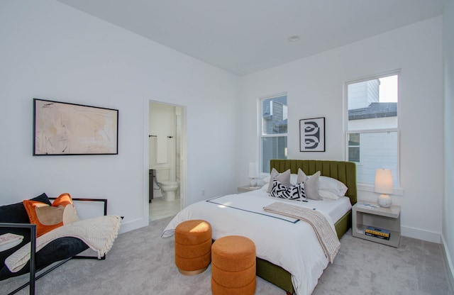 bedroom with ensuite bath and light carpet