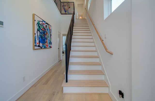 stairway with a towering ceiling and hardwood / wood-style floors