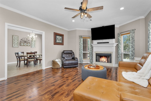 living room featuring crown molding, a large fireplace, wood-type flooring, and ceiling fan with notable chandelier