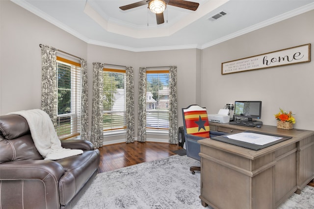 office with wood finished floors, ornamental molding, visible vents, ceiling fan, and a tray ceiling