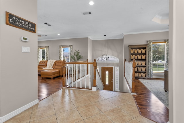 foyer entrance with light tile patterned floors, an inviting chandelier, and crown molding