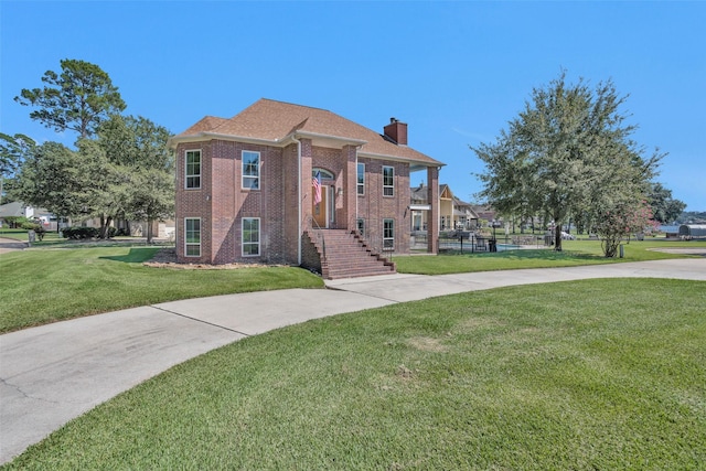 view of front of house with fence, a front yard, a chimney, and brick siding