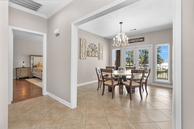 tiled dining space featuring french doors, a chandelier, a textured ceiling, and ornamental molding