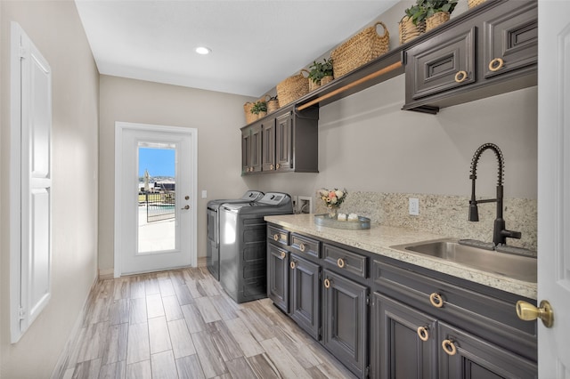 washroom with cabinets, independent washer and dryer, light hardwood / wood-style floors, and sink