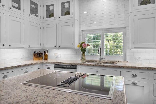 kitchen featuring tasteful backsplash, stainless steel dishwasher, cooktop, sink, and white cabinets