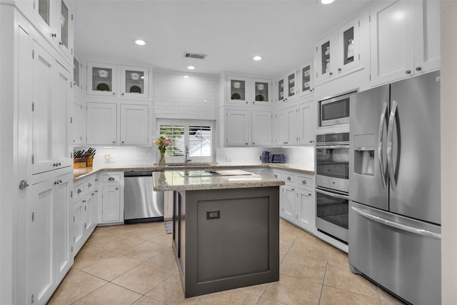 kitchen with white cabinetry, stainless steel appliances, light tile patterned floors, tasteful backsplash, and a kitchen island