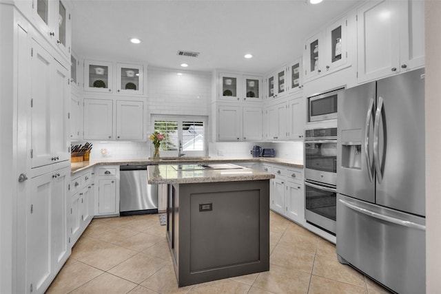 kitchen featuring glass insert cabinets, a kitchen island, white cabinetry, and appliances with stainless steel finishes