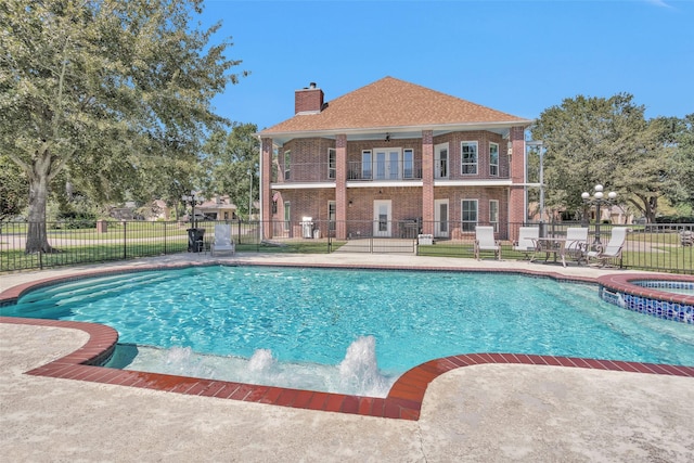 view of swimming pool featuring a pool with connected hot tub, fence, ceiling fan, and a patio area