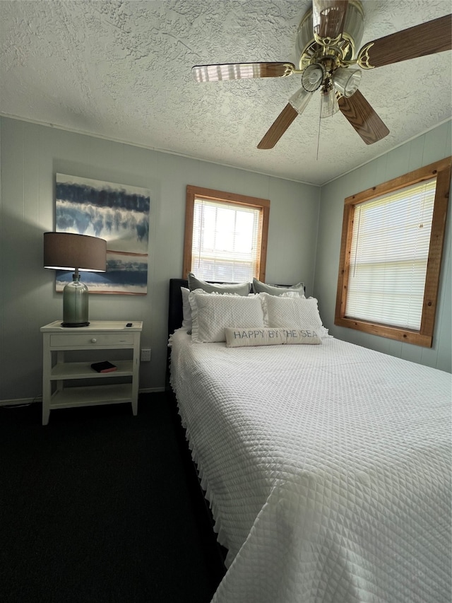 bedroom with ceiling fan, carpet floors, and a textured ceiling