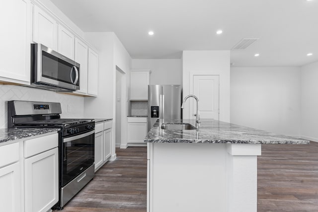 kitchen with a center island with sink, white cabinetry, stainless steel appliances, and dark hardwood / wood-style floors