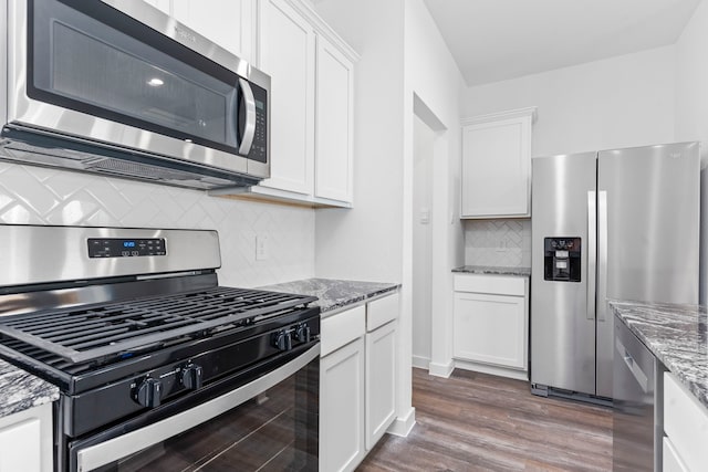 kitchen with appliances with stainless steel finishes, white cabinets, stone countertops, and dark wood-type flooring