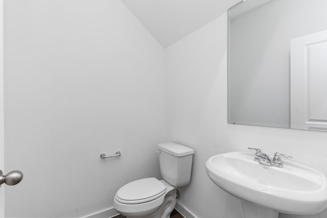 bathroom featuring sink, toilet, and vaulted ceiling