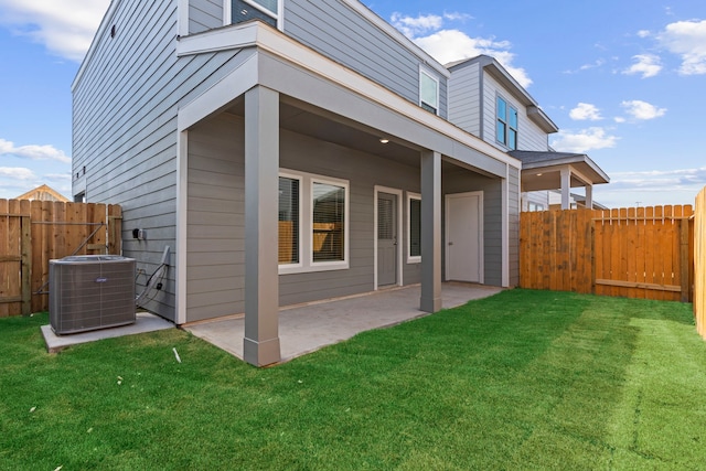 back of house with cooling unit, a patio, and a lawn