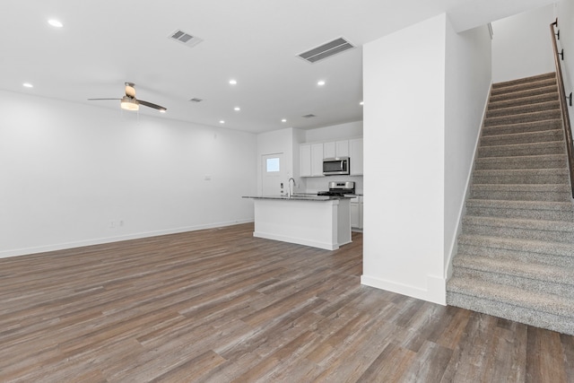 unfurnished living room with a barn door, hardwood / wood-style flooring, sink, and ceiling fan