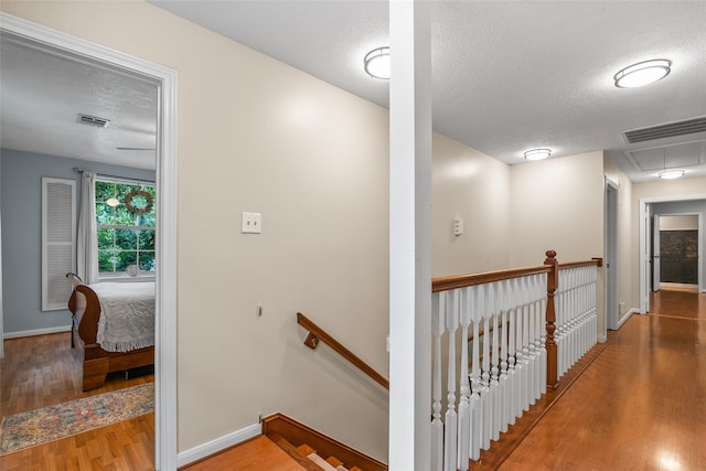 hall with a textured ceiling and light hardwood / wood-style floors