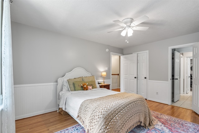 bedroom featuring ceiling fan, a textured ceiling, and light hardwood / wood-style flooring