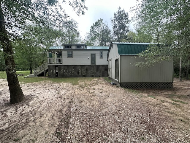 rear view of property featuring a wooden deck and a shed